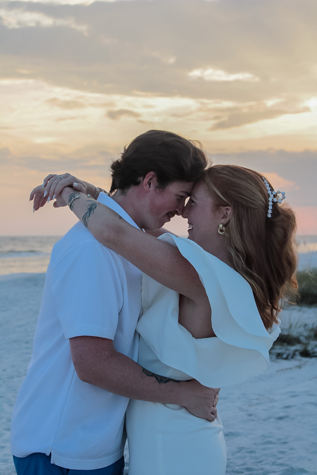 Couple dressed in white embracing on the Gulf Coast at sunset